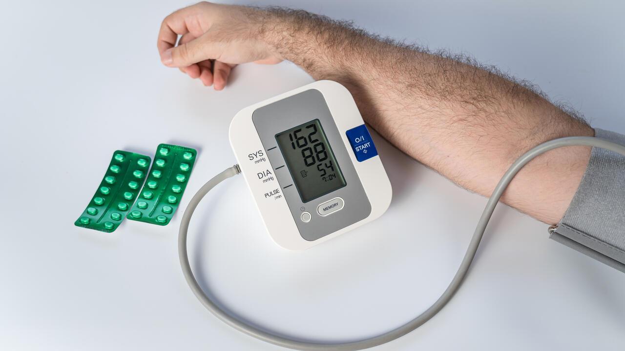 A person is measuring their blood pressure with a digital monitor.