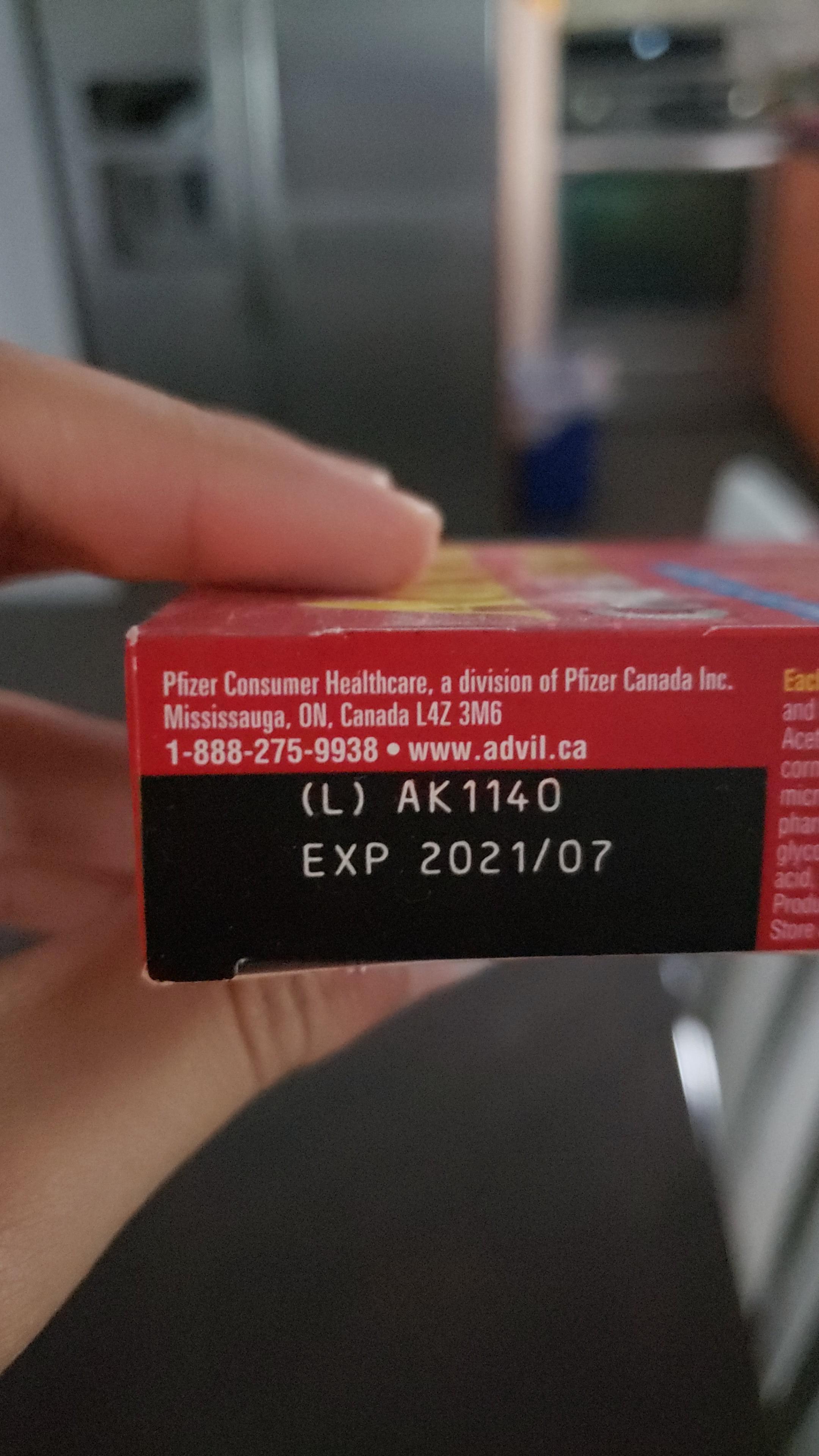 A red and white box of Advil pills with a label showing the product name, manufacturer, and expiration date.