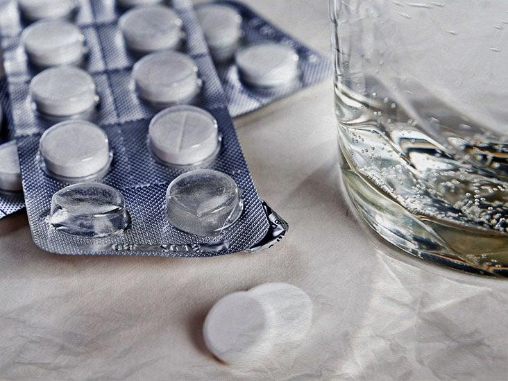 A blister pack of pills next to a glass of water.