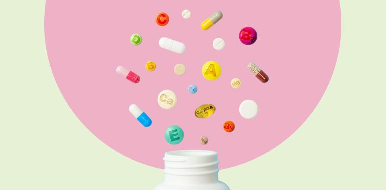Colorful pills and capsules burst out of a white bottle against a pink background.
