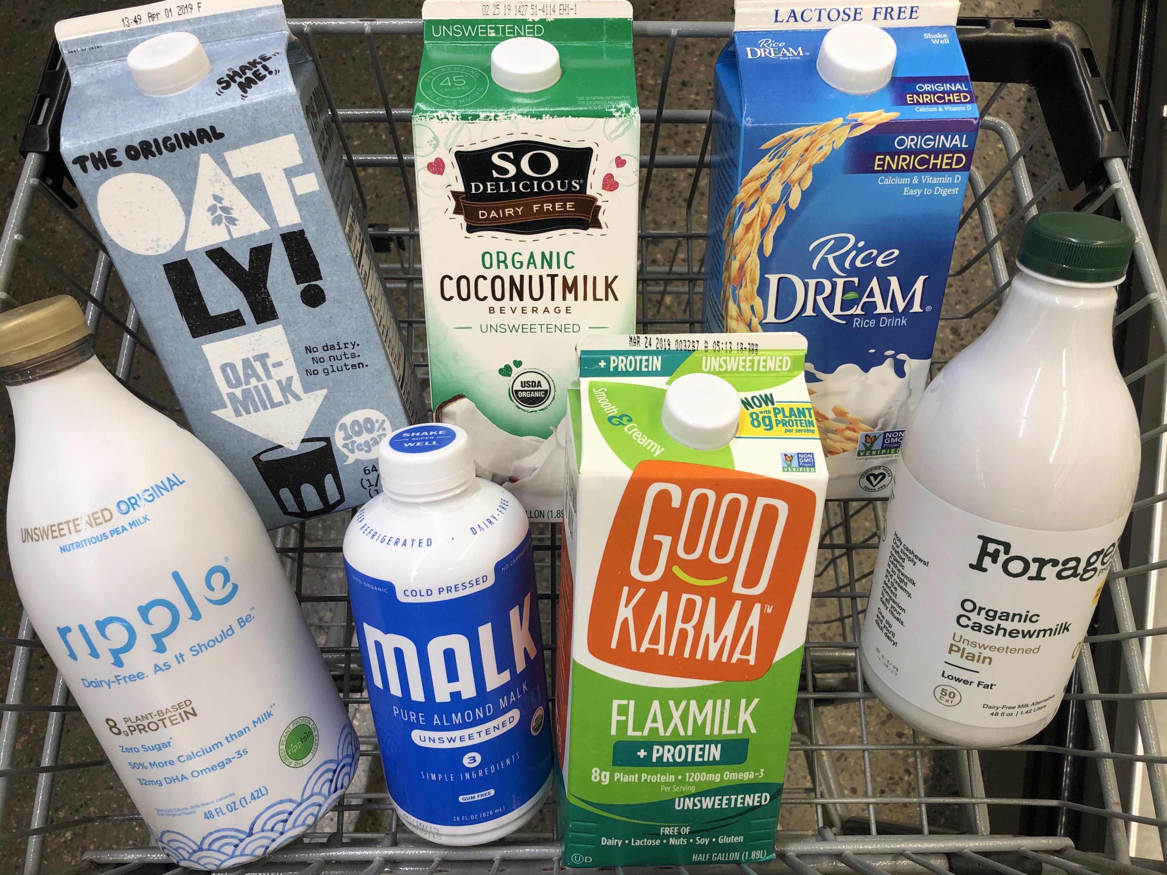 A variety of milk alternatives in a grocery cart.
