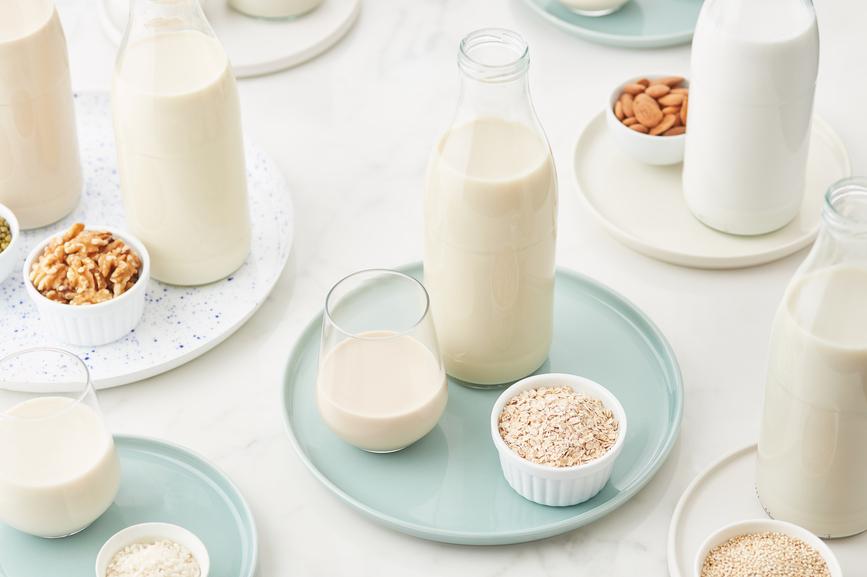 Bottles and glasses of different types of plant-based milk.