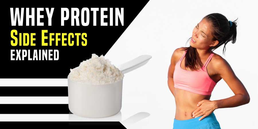 A young woman in a pink sports bra holds her stomach in pain next to a large white scoop of whey protein powder.