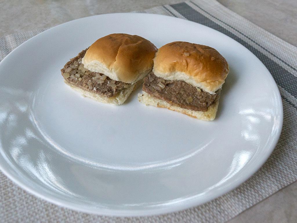 Two small hamburgers on a white plate.