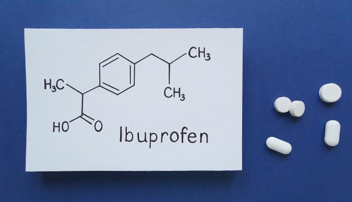 Ibuprofen pills and the chemical formula of ibuprofen on a blue background.
