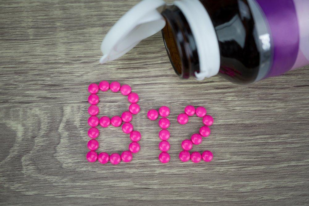 Pink pills forming the letters B12 next to an open bottle of pills.