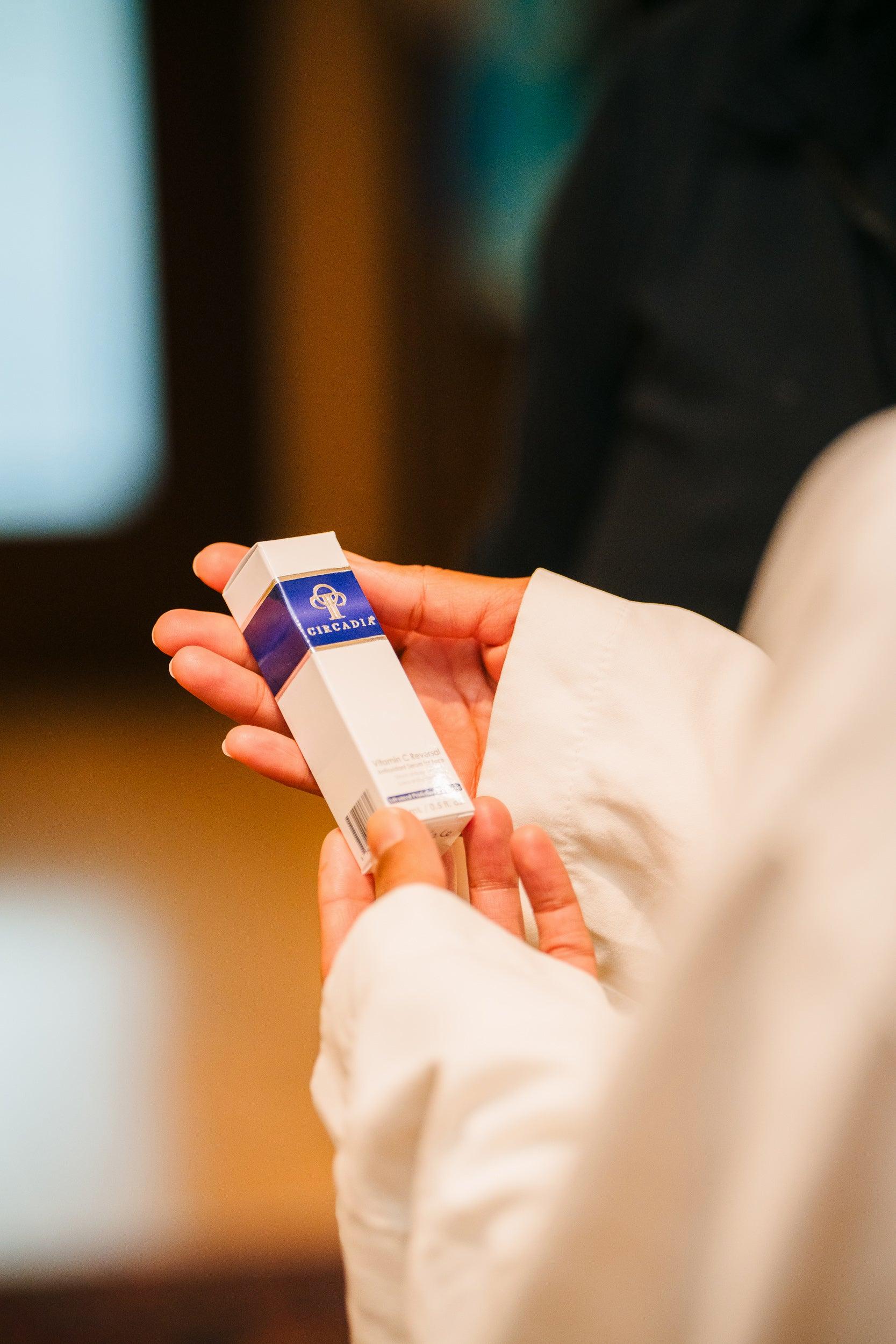 A womans hand holding a white and blue box of Cindella skin cream.