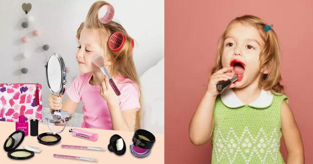 Two young girls are playing with makeup, one is putting lipstick on and the other is putting eye shadow on.