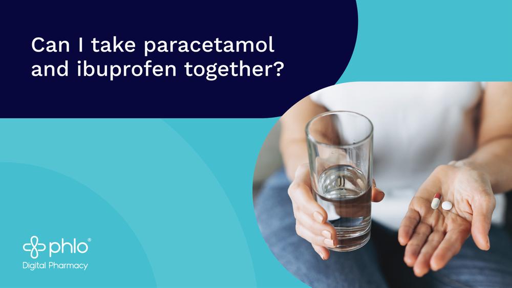 A person holds a glass of water in one hand and two pills in the other hand.