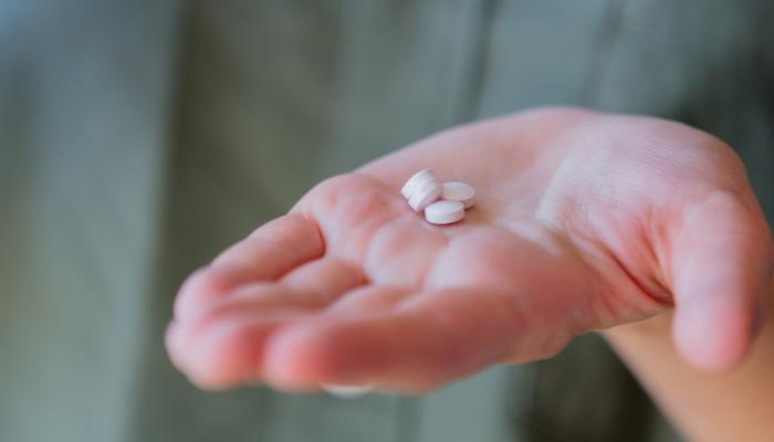An open hand holding three white pills.