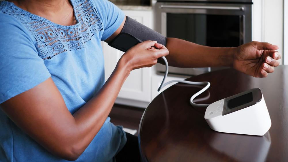 A woman is checking her blood pressure with a digital blood pressure monitor.
