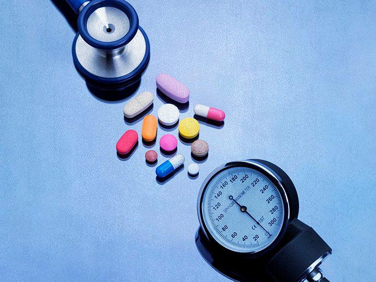 A stethoscope and pills on a blue table.