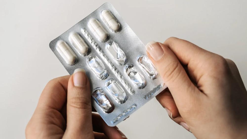 A hand holding a blister pack of pills.