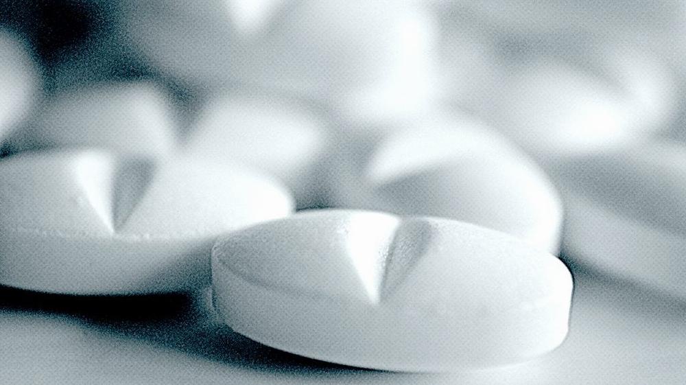 Close-up of white pills with a V-shaped imprint.