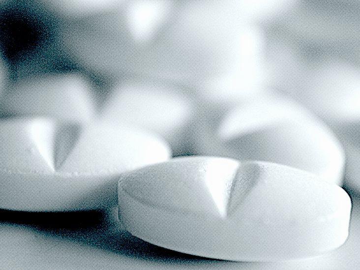 Close-up of white pills with a V-shaped imprint.