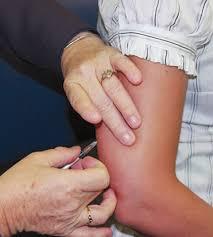 A person injects a vaccine into a patients arm.