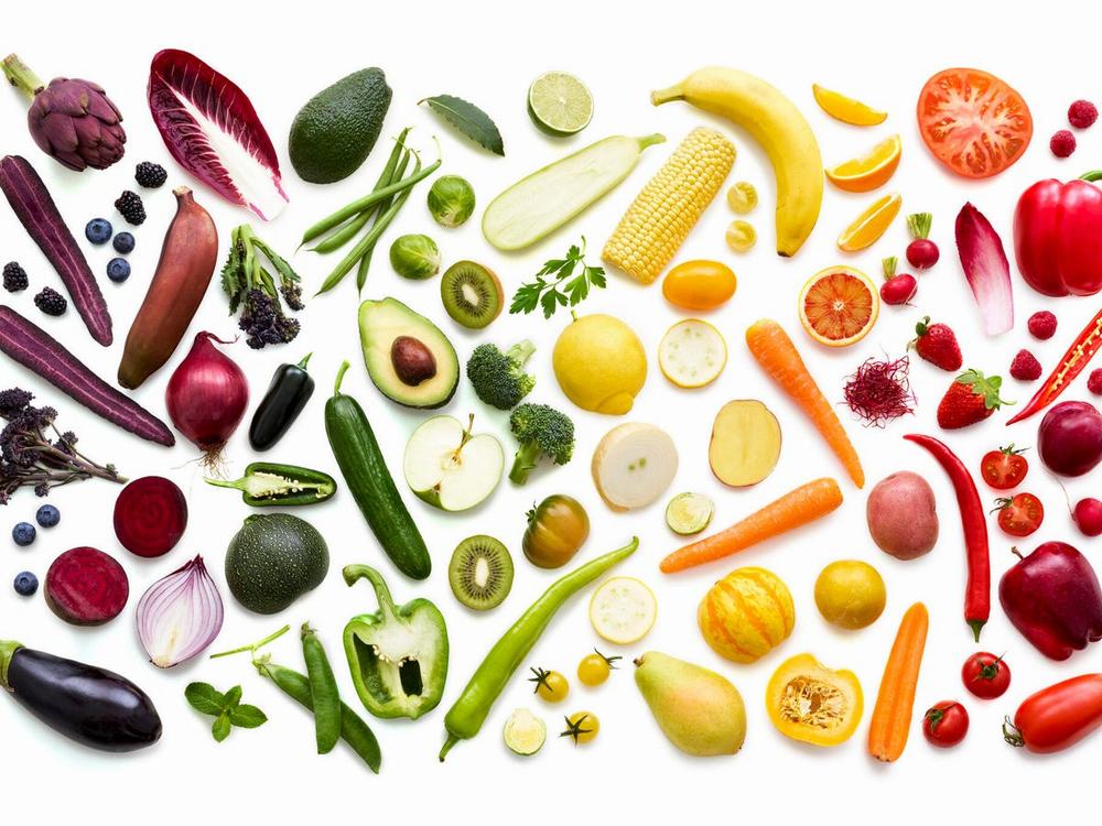 An assortment of fruits and vegetables of different colors arranged in a rainbow pattern.