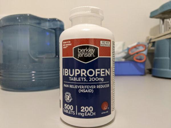A white bottle of Ibuprofen tablets on a table.
