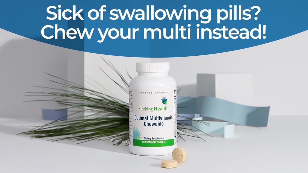 A bottle of Seeking Health Optimal Multivitamin chewable tablets next to two tablets on a blue background with white pine needles.
