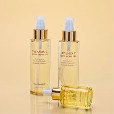 Three clear bottles of Vitamin C Glow Body Oil with gold caps.