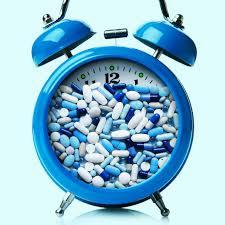 A blue alarm clock is filled with a variety of pills and capsules.