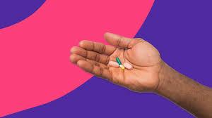A brown-skinned persons hand is holding three pills.