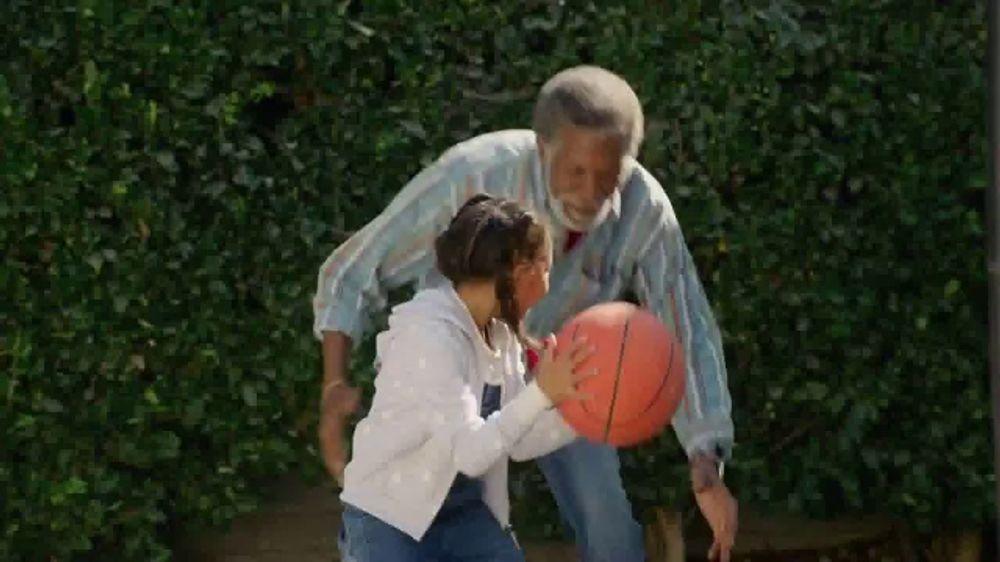 An African-American grandfather is playing basketball with his granddaughter in the backyard.
