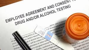 A document titled Employee Agreement and Consent to Drug and/or Alcohol Testing sits on a table next to a pen and pill bottle.
