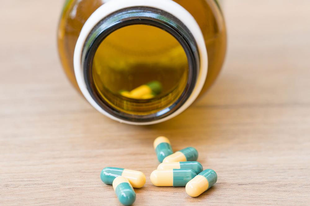 Green and yellow pills spilled out of a brown bottle.