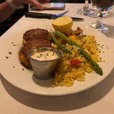 A plate of food with two crab cakes, asparagus, and rice pilaf.